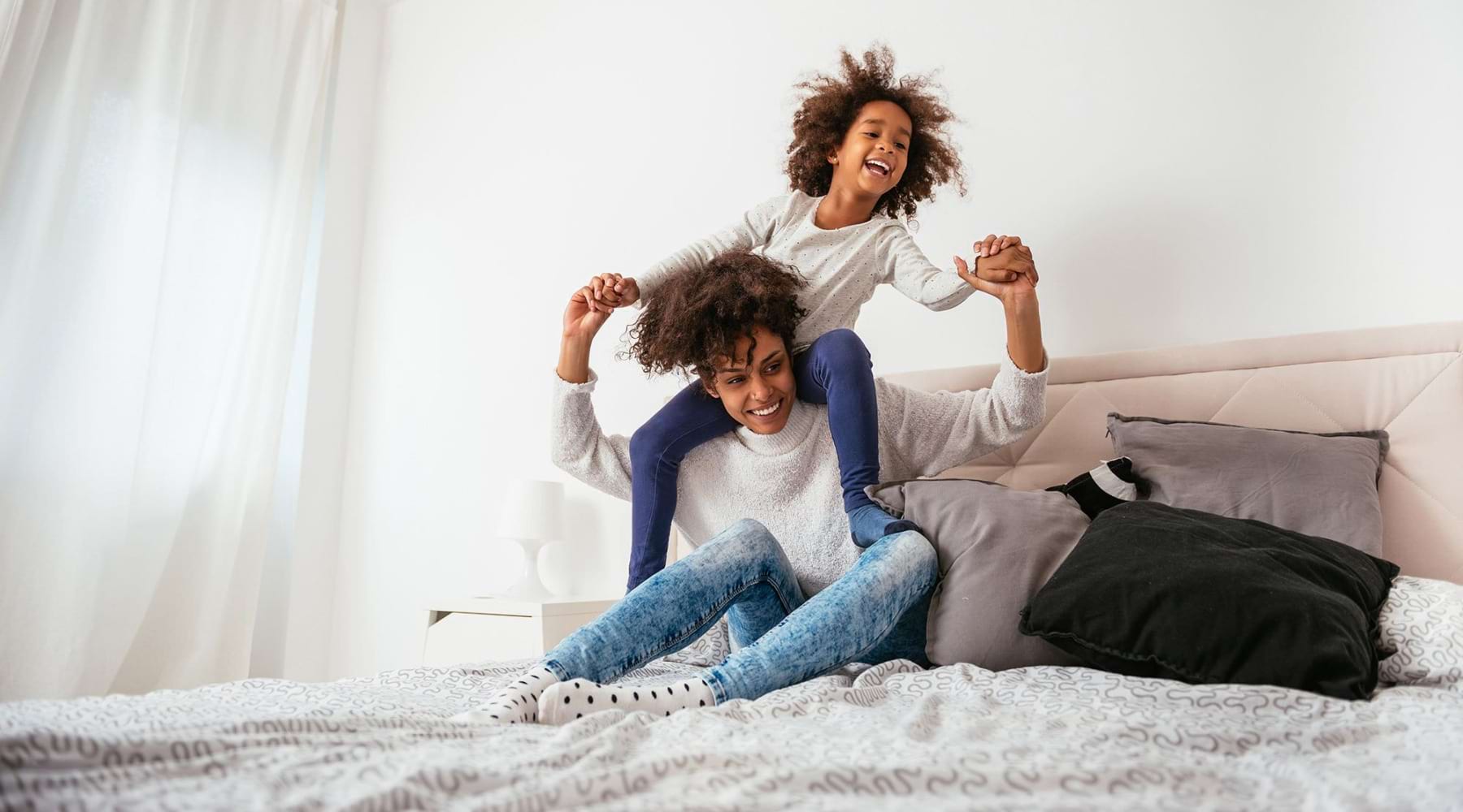 a mom and daughter playing in a bed
